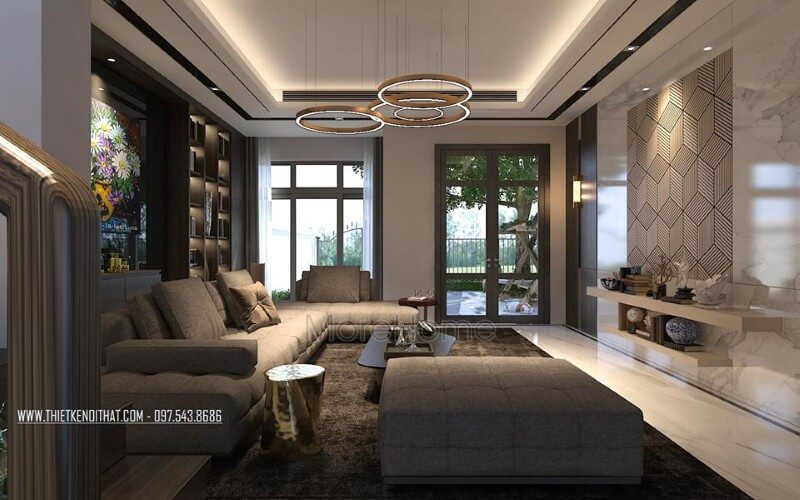 Phòng khách hiện đại sắc trầm nhưng rộng rãi, thông thoáng với cửa sổ, cửa chính kính lớn. Thiết kế nội thất